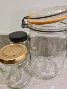 A photo of three empty jars, one with an orange rubber seal, one with a black lid and one with a gold lid.