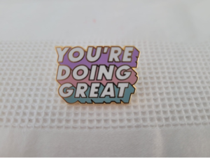 A pin badge which says 'You're Doing Great'